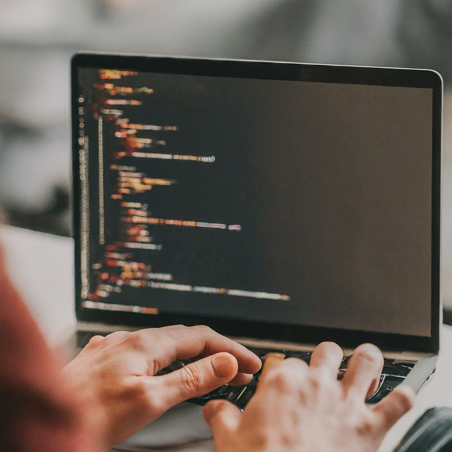 A person sitting at a computer, looking confused and frustrated while typing code. The person's screen is filled with lines of code that they don't understand.